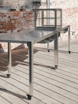 Development and production of three stainless steel tables with an integrated fireplace and rotatable arms with hooks to hang cheese over heat, a glass vitrine and small storage spaces by ErtlundZull. Development and production of three wall mounted stainless steel shelves and a four-legged roof by ErtlundZull, Gerswalde 2021. Concept by Argument GmbH. Photos by Studio Bowie. ErtlundZull