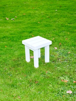 White aluminium stool from the furniture series Pretending It's Wood. Placed on bright green grass. Designed by ErtlundZull. Photographed by Robert Hamacher. ErtlundZull