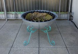A mirrored roundshaped compost sculpture standing on ornamental legs in an outside area. ErtlundZull