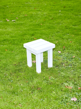 White aluminium stool from the furniture series Pretending It's Wood. Placed on bright green grass. Designed by ErtlundZull. Photographed by Robert Hamacher. ErtlundZull